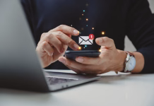 Slovnični nasvet: s SMS ali z SMS? Hand of businessman using smartphone for email with notification alert, Online communication concept.
