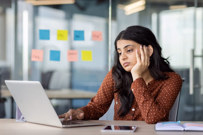 latin-american-businesswoman-appears-stressed-at-work-gazing-at-laptop-screen-in-modern-office-creative-ideas-on-sticky-notes-surround-her-with-smartphone-by-her-side-reflecting-focus-stockpack-istock Latin American businesswoman appears stressed at work, gazing at laptop screen in modern office. Creative ideas on sticky notes surround her, with smartphone by her side, reflecting focus.