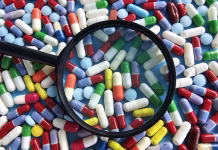 5 najpogosteje predpisanih zdravil Many colorful pills and capsules spread across a surface with a magnifying glass on them