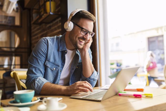 smiling-young-man-listening-mujsic-at-the-coffee-shop-stockpack-istock Smiling young man listening mujsic at the coffee shop