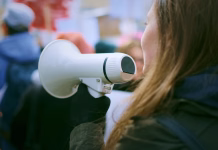 Nova mladinska podnebna delegatka je Meta Štuhec Young woman with megaphone at a demonstration in the city.