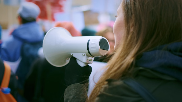 Young woman with megaphone at a demonstration in the city.
