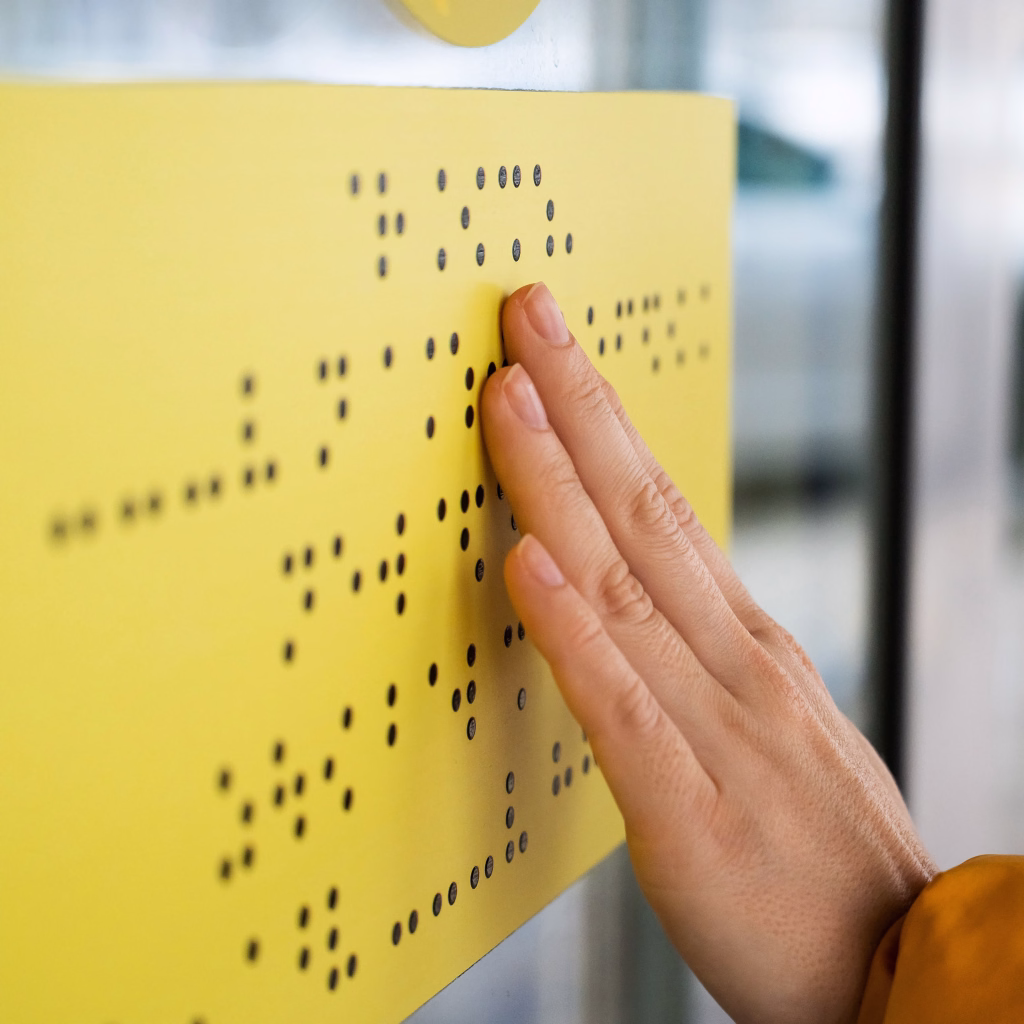 Close-up of a woman reading a braille lettering on a glass door
