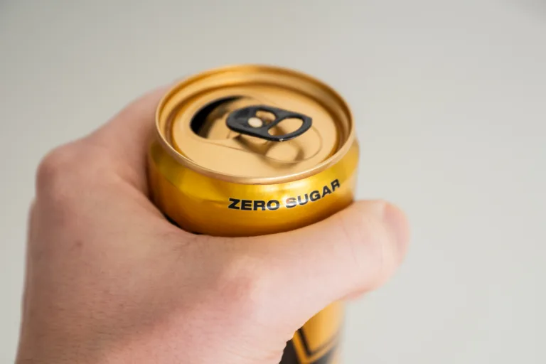 close up of hand holding a zero sugar soda can.