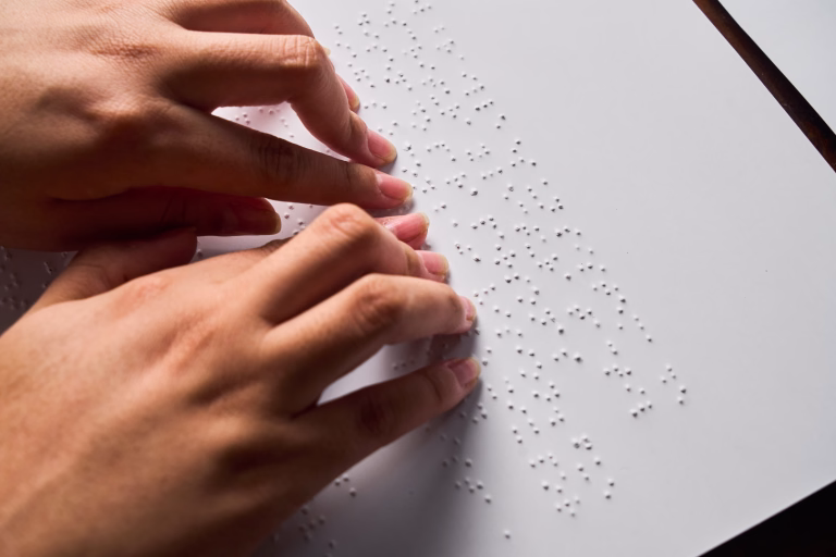 Hands of a blind person reading some braille text touching the relief.