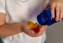 Zeleni gumiji, ki jih promovirajo vplivneži: So koristni ali le viralni nateg? Kid hand hold a bottle from which colorful vitamins in the shape of jelly bears have poured out. Multivitamins or jelly candies for children. Vitamins for children.