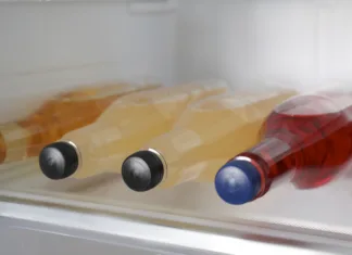 Nasvet za vroče dni: koliko minut pustiti pijačo v zamrzovalniku? Many different cold drinks in refrigerator, closeup