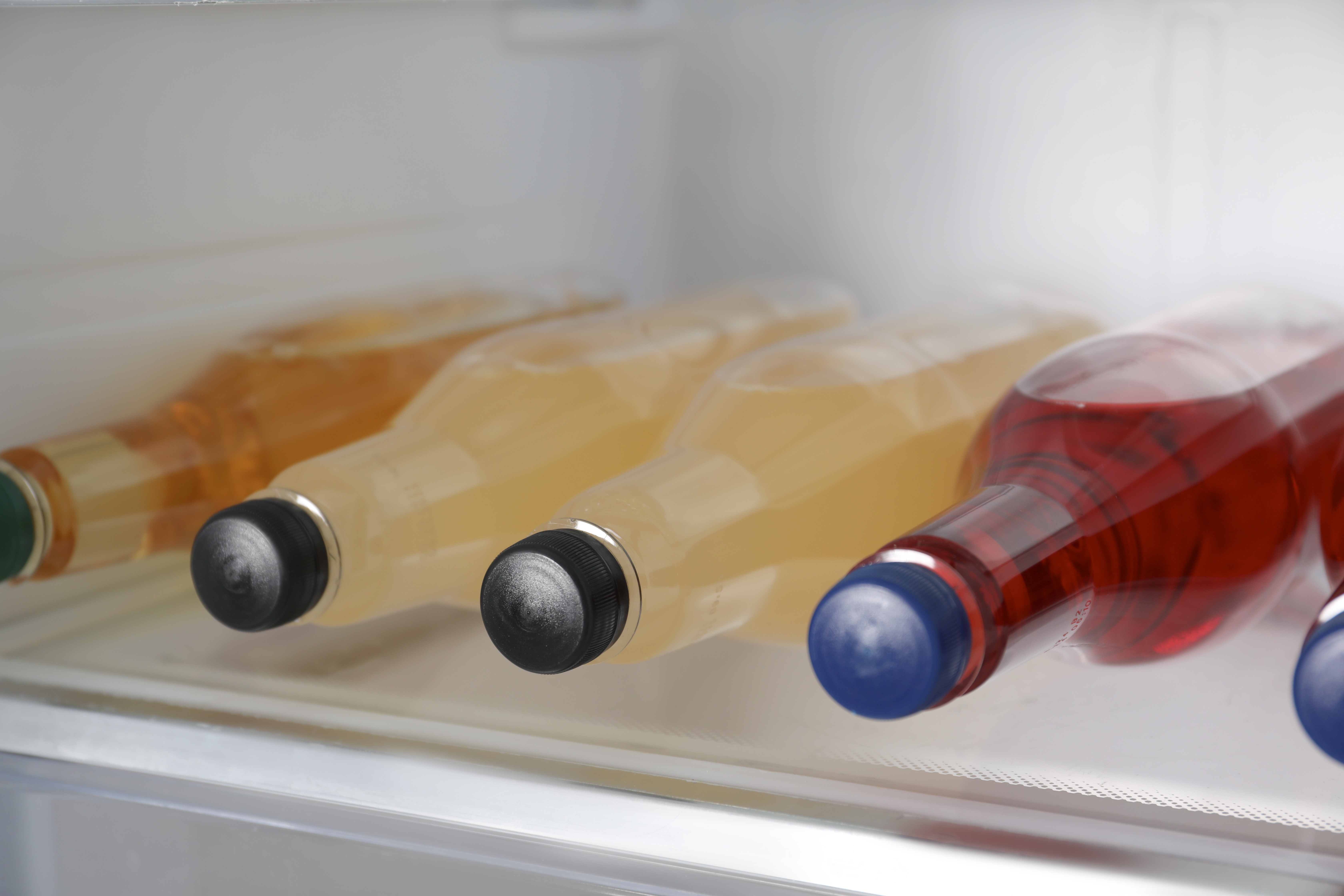 Nasvet za vroče dni: koliko minut pustiti pijačo v zamrzovalniku? Many different cold drinks in refrigerator, closeup