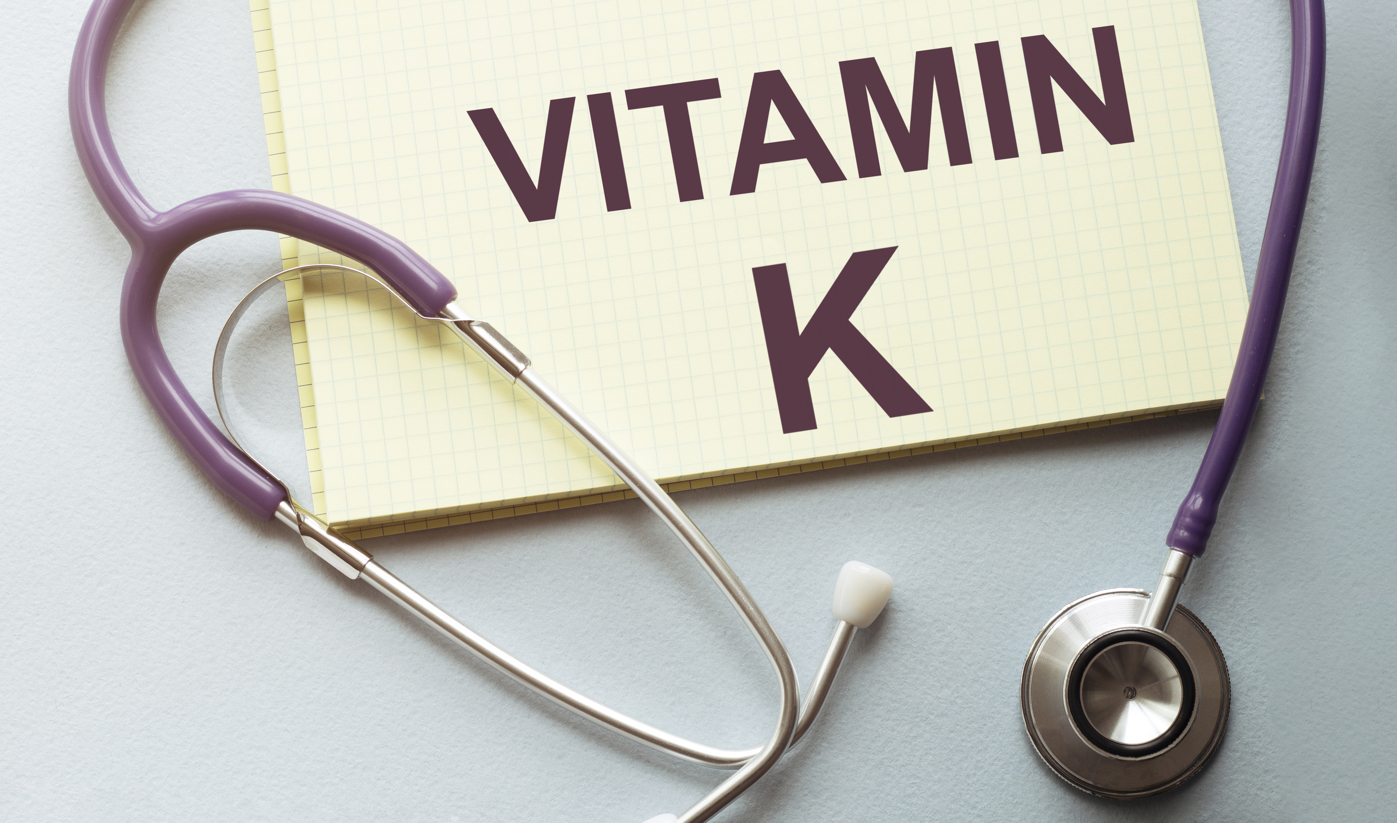 On a purple background a stethoscope with yellow list for you text vitamin k
