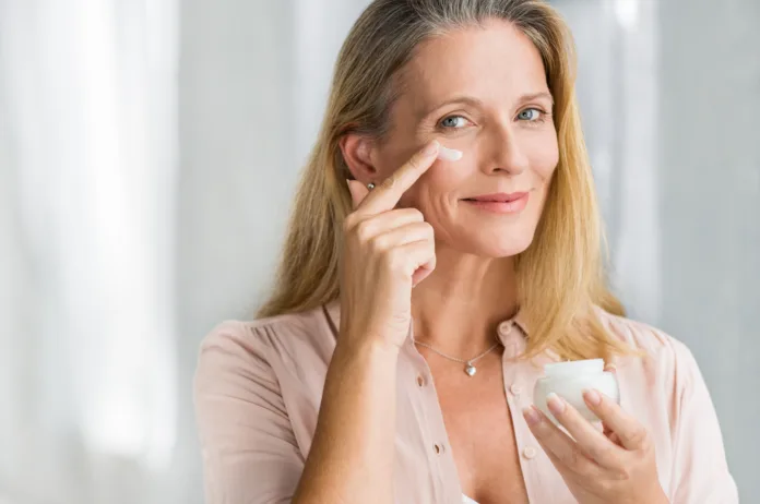 smiling-senior-woman-applying-anti-aging-lotion-to-remove-dark-circles-under-eyes-happy-mature-woman-using-cosmetic-cream-to-hide-wrinkles-below-eyes-lady-using-day-moisturizer-to-counteract-the-aging-stockpack-istock Smiling senior woman applying anti-aging lotion to remove dark circles under eyes. Happy mature woman using cosmetic cream to hide wrinkles below eyes. Lady using day moisturizer to counteract the aging of the skin.