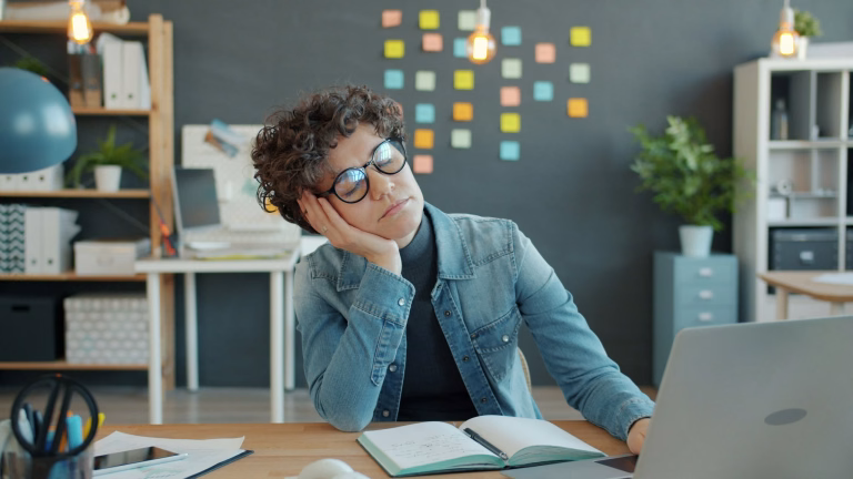 Tired woman is sleeping at desk in workplace then waking up and working with laptop feeling sleepy and exhausted. Modern technology and deadline concept.