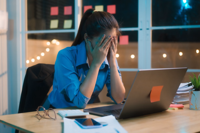 working-late-into-the-night-asian-woman-appears-stressed-and-overwhelmed-at-her-desk-rubbing-her-forehead-as-if-experiencing-migraine-or-headache-surrounded-by-paperwork-and-dimly-lit-office-stockpack-istock Working late into the night, Asian woman appears stressed and overwhelmed at her desk, rubbing her forehead as if experiencing migraine or headache, surrounded by paperwork and dimly lit office.