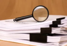 Po 100 letih razvozlali Schrödingerjevo skrivnost A magnifying glass rests on scattered clipped papers, symbolizing diligent research and careful analysis