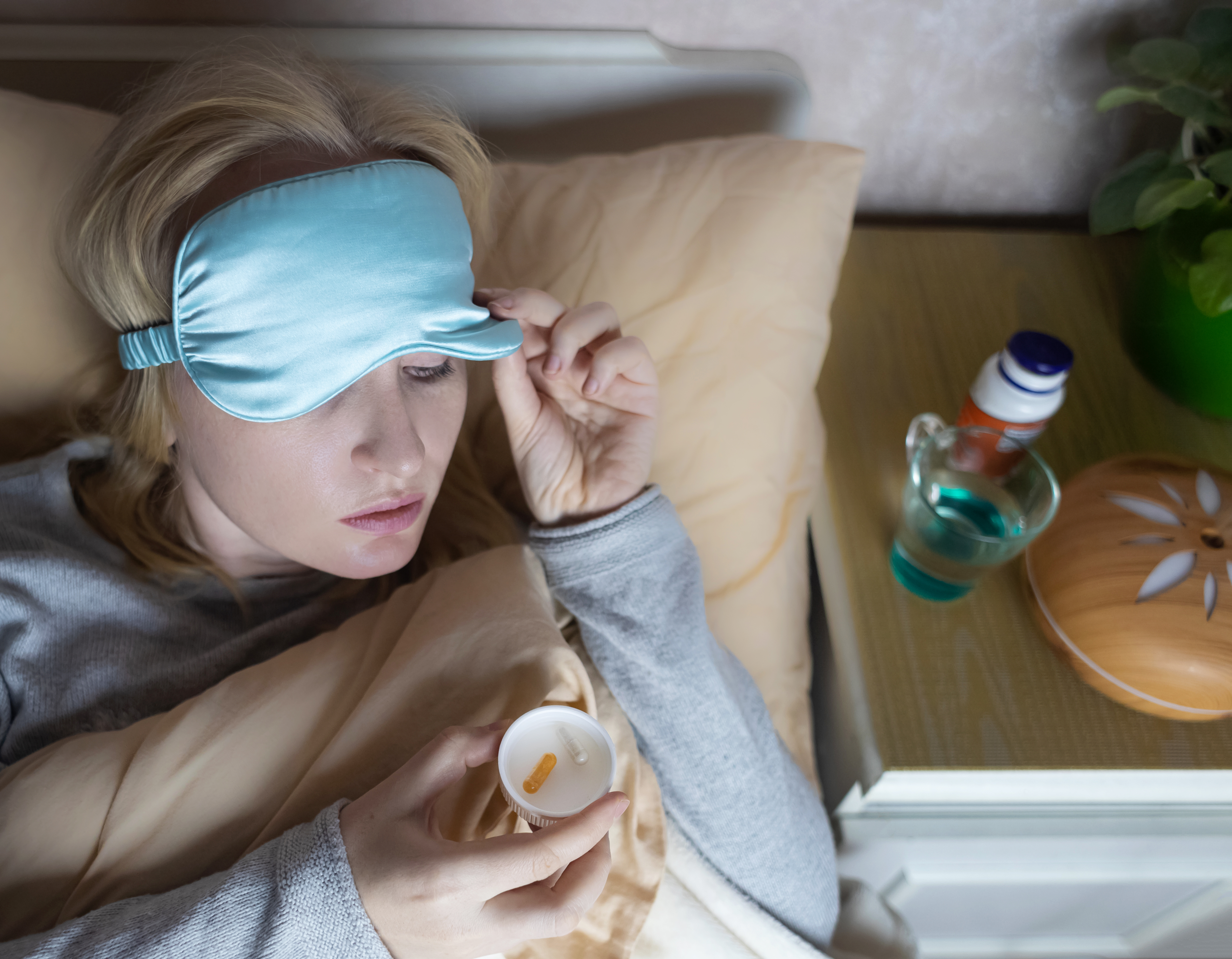 A woman cannot fall asleep and wants to drink a capsule with melatonin, a sleeping pill. Regulation of biological rhythms. Manifestations of jitlag or insomnia.