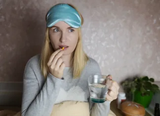 To so učinki, ki jih ima dodatek melatonina na telo: Vse kaže na to, da ni le uspavalni hormon A woman cannot fall asleep and wants to drink a capsule with melatonin, a sleeping pill. Regulation of biological rhythms. Manifestations of jitlag or insomnia.