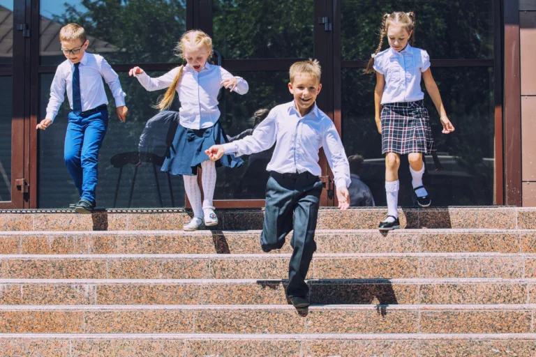 Beautiful school children active and happy on the background of school in uniform