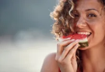 5 živil, ki odlično hidrirajo telo: obvezno jih jejte med hudo vročino Beautiful young woman with curly hair biting on watermelon piece. Summertime, lifestyle concept.