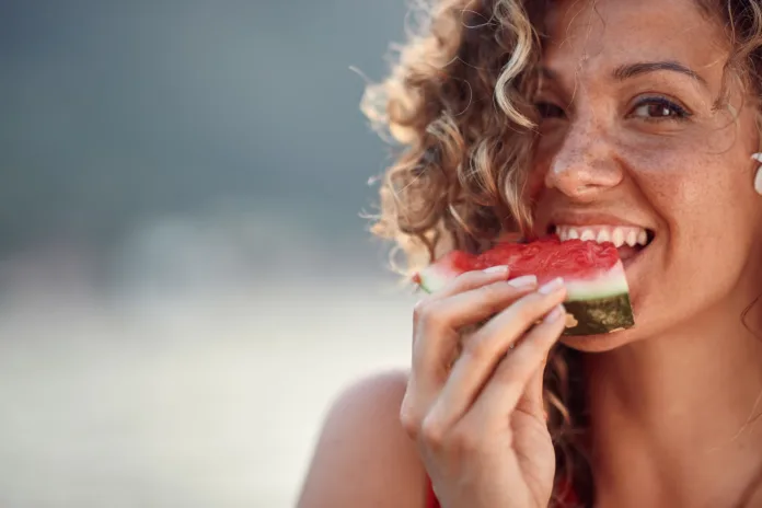 beautiful-young-woman-with-curly-hair-biting-on-watermelon-piece-summertime-lifestyle-concept-stockpack-istock Beautiful young woman with curly hair biting on watermelon piece. Summertime, lifestyle concept.