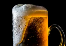 Ste pozabili dati pivo v hladilnik? Ta trik ga ohladi v samo dveh minutah Velik kozarec piva, ki se preliva s peno in mehurčki, izoliran na črnem ozadju.