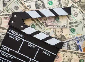 Kultura filmskih predelav: zakaj Hollywood reciklira? Cinema clapperboard on stack US dollars banknote bill background - Movie entertainment industry to make money concept.