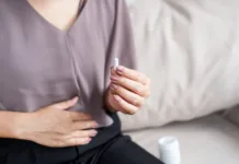 Veliko ljudi jemlje probiotike napačno: Ali jih tudi vi? Close-up of a woman’s hand holding a white pill, taking medicine to help relieve stomach pain or digestive problems like IBS, constipation, or diarrhea, aiming to improve her comfort