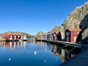 Colorful boathouses in Smögen. Fisherman's huts. Panoramic view of colorful wooden houses along the rocky cliff on the sea channel shore in the old fishing harbor on a sunny day, Sweden.