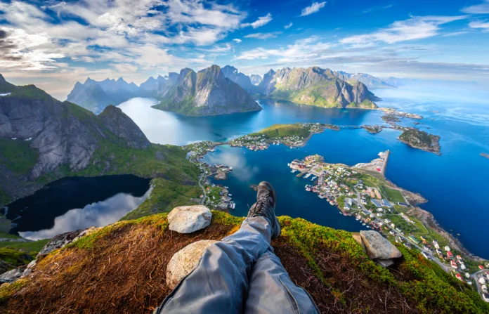 First person perspective shot from a hiker sitting at the edge of a cliff at Lofoten is an archipelago in the county of Nordland, Norway Landscape town of Reine. Fisheye lens landscape town of Reine.