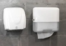 Večina ljudi ne ve, kaj je bolj higienično: Bi izbrali papirnate brisače ali sušilnik? Paper towel dispenser and hand dryer on concrete wall on modern stylish bathroom in loft style