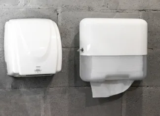 Večina ljudi ne ve, kaj je bolj higienično: Bi izbrali papirnate brisače ali sušilnik? Paper towel dispenser and hand dryer on concrete wall on modern stylish bathroom in loft style