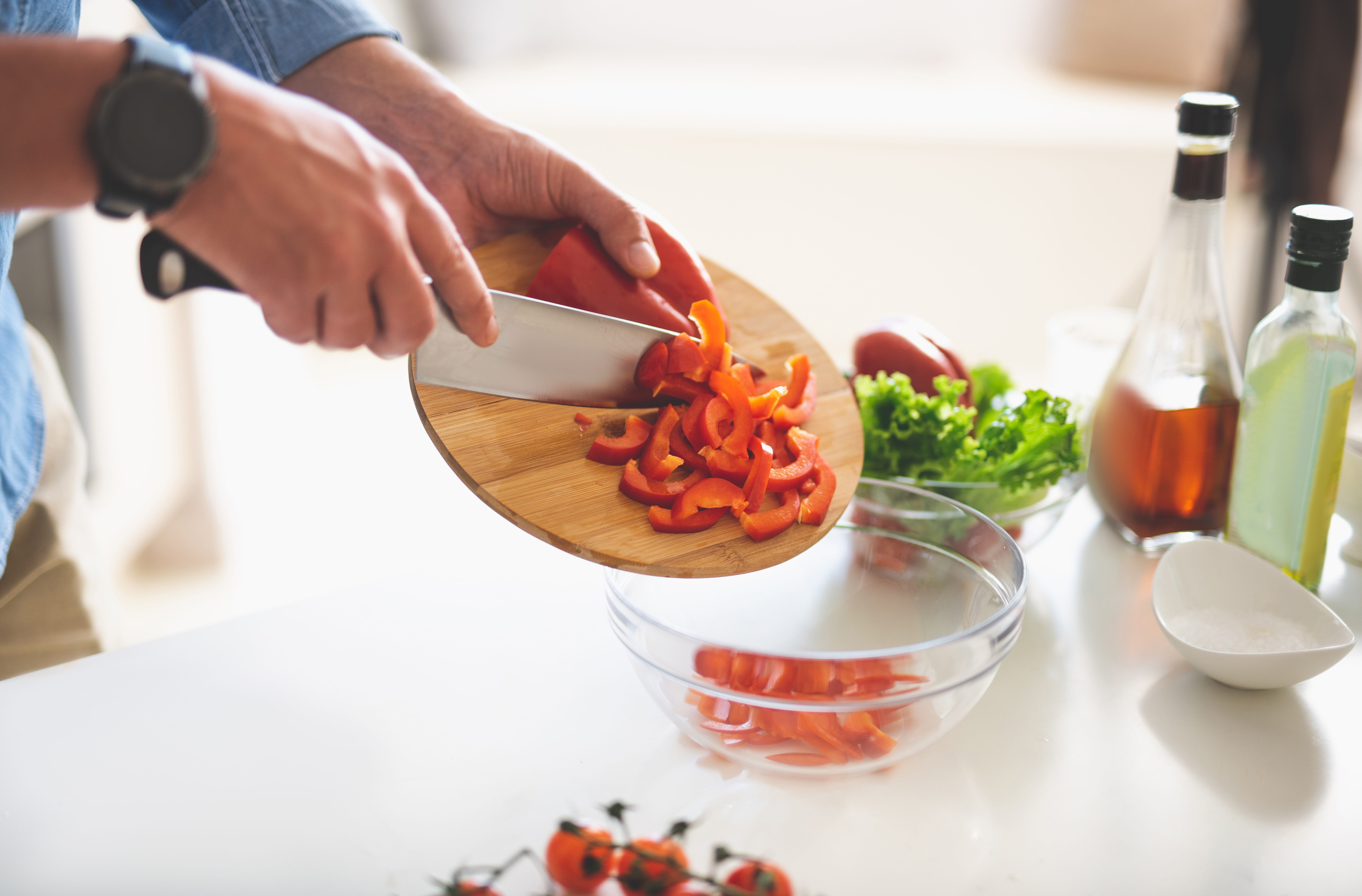 Preparing ingredients. Close up of male hands holding knife and cutting board with chopped bell pepper
