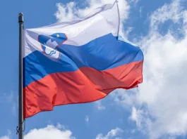 Slovenian national flag waving on blue sky background. Republic of Slovenia, SL
