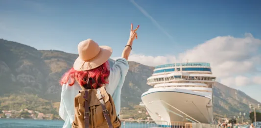 Tourist wearing backpack and hat gesturing near cruise ship at Kotor bay, Montenegro