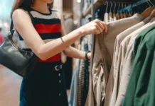 5 modnih trendov, ki jih bodo mladi nosili v drugi polovici leta 2026 Asian woman shopping clothes in shoping mall. Customer choosing japanese fashion clothing hangers shelf. Weekend activity lifestyles of single person