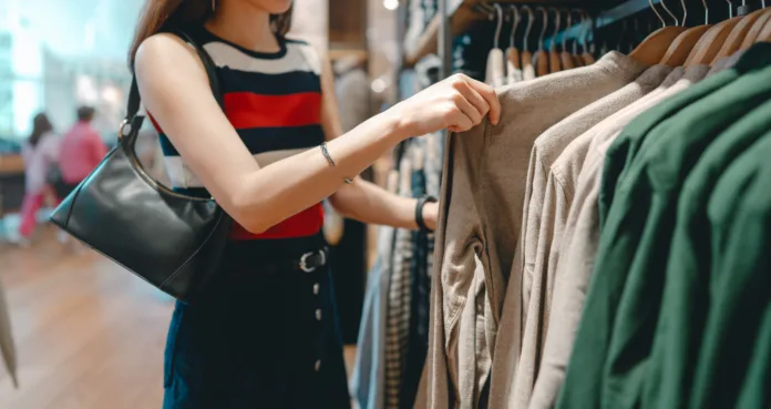Asian woman shopping clothes in shoping mall. Customer choosing japanese fashion clothing hangers shelf. Weekend activity lifestyles of single person