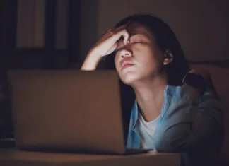 Kako preživeti izpitno obdobje brez neprespanih noči in hektolitrov kave? Asian woman student or businesswoman work late at night. Concentrated and feel sleepy at the desk in dark room with laptop or notebook.Concept of people workhard and burnout syndrome.