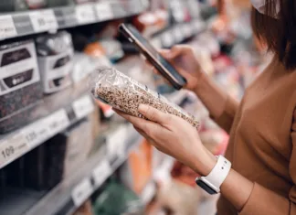 Nateg na trgovskih policah ali vrhunsko premišljen marketing? Ali ti izdelki res upravičijo astronomske cene? Closeup - Woman shopping in supermarket and reading product information. Costumer buying food at the market.
