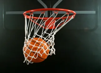 Prihodnost evropske košarke v Stožicah: Kdaj igrajo mladi slovenski upi? Detail of basketball ball hitting the hoop, top view. Isolated on black background. Freeze motion of sport action.