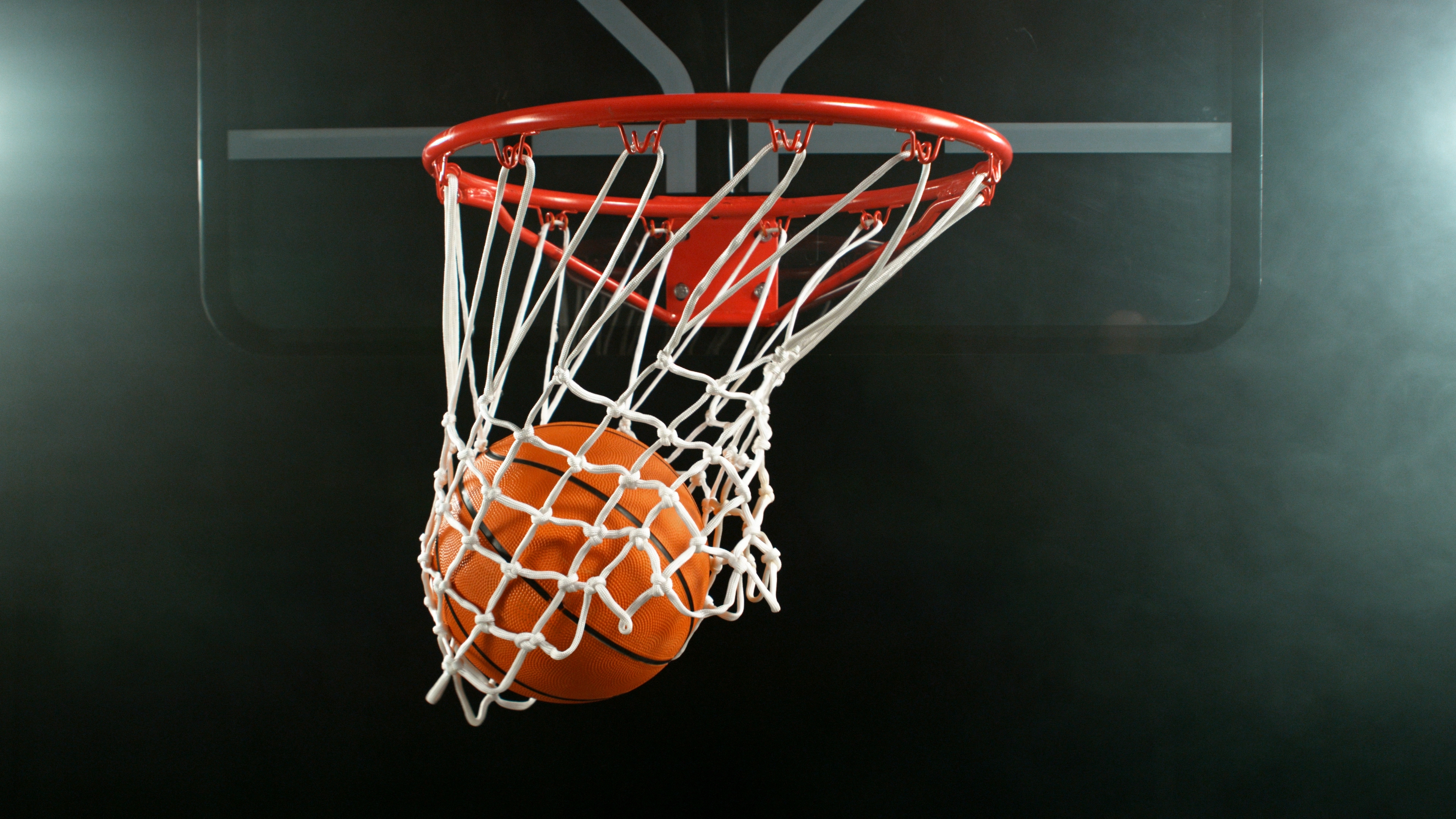 Prihodnost evropske košarke v Stožicah: Kdaj igrajo mladi slovenski upi? Detail of basketball ball hitting the hoop, top view. Isolated on black background. Freeze motion of sport action.