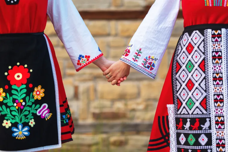 Girls in traditional bulgarian ethnic costumes with folklore embroidery holding hands. The spirit of Bulgaria - culture, history and traditions.