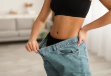 Ali ta znana zdravila povzročajo povečanje telesne teže? Great Weight Loss Result. Unrecognizable Fit Black Lady Showing Abdominal Muscles And Flat Belly Wearing Old Oversized Jeans After Successful Slimming Indoor. Cropped Shot