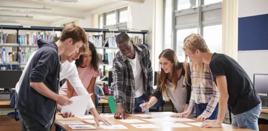 Group Of College Students Collaborating On Project In Library