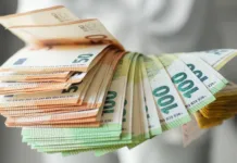 Skrivnostni varčevalni sistem milijarderjev: Kako upravljati z denarjem kot elita Hand holding large fan of euro banknotes in 50, 100, and 200 denominations, concept of abundance, wealth, success and financial prosperity