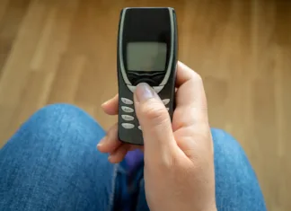 Pametni telefoni so uradno ‘iz mode’: Zakaj mladi raje kupujejo stare Nokia telefone na tipke? In the hands of an old model of mobile phone in the office