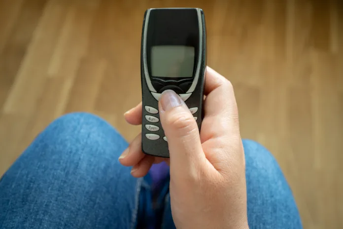 in-the-hands-of-an-old-model-of-mobile-phone-in-the-office-stockpack-istock In the hands of an old model of mobile phone in the office