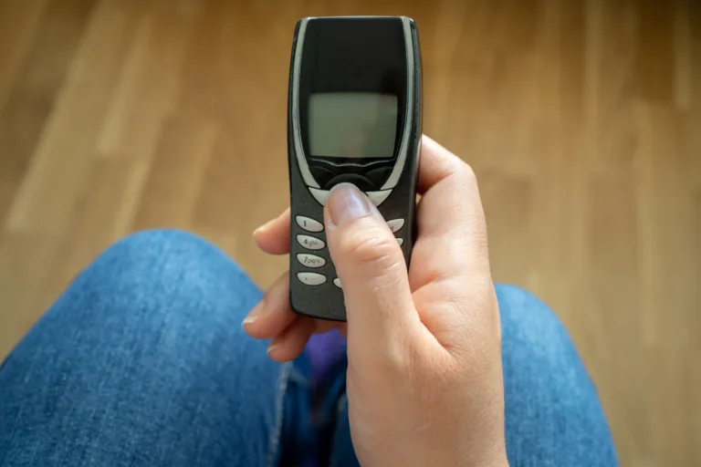 In the hands of an old model of mobile phone in the office