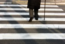 Koliko korakov na dan so imeli ljudje pred 100 leti? Legs and shadow of a senior person using walking cane while crossing the street in motion blur