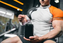 To znano prehransko dopolnilo bi lahko pomagalo zdraviti raka? muscular bodybuilding athlete with perfect body holding protein or whey jar mockup in gym, athletic man with in fitness club preparing sport nutrition and supplement. High quality photo