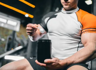 To znano prehransko dopolnilo bi lahko pomagalo zdraviti raka? muscular bodybuilding athlete with perfect body holding protein or whey jar mockup in gym, athletic man with in fitness club preparing sport nutrition and supplement. High quality photo
