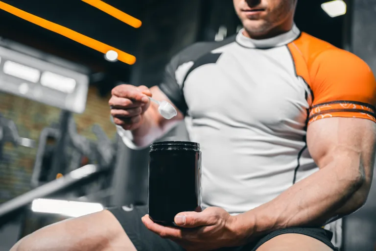 muscular bodybuilding athlete with perfect body holding protein or whey jar mockup in gym, athletic man with in fitness club preparing sport nutrition and supplement. High quality photo