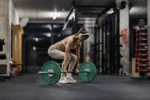 Powerful muscular female bodybuilder lifting barbell at gym.